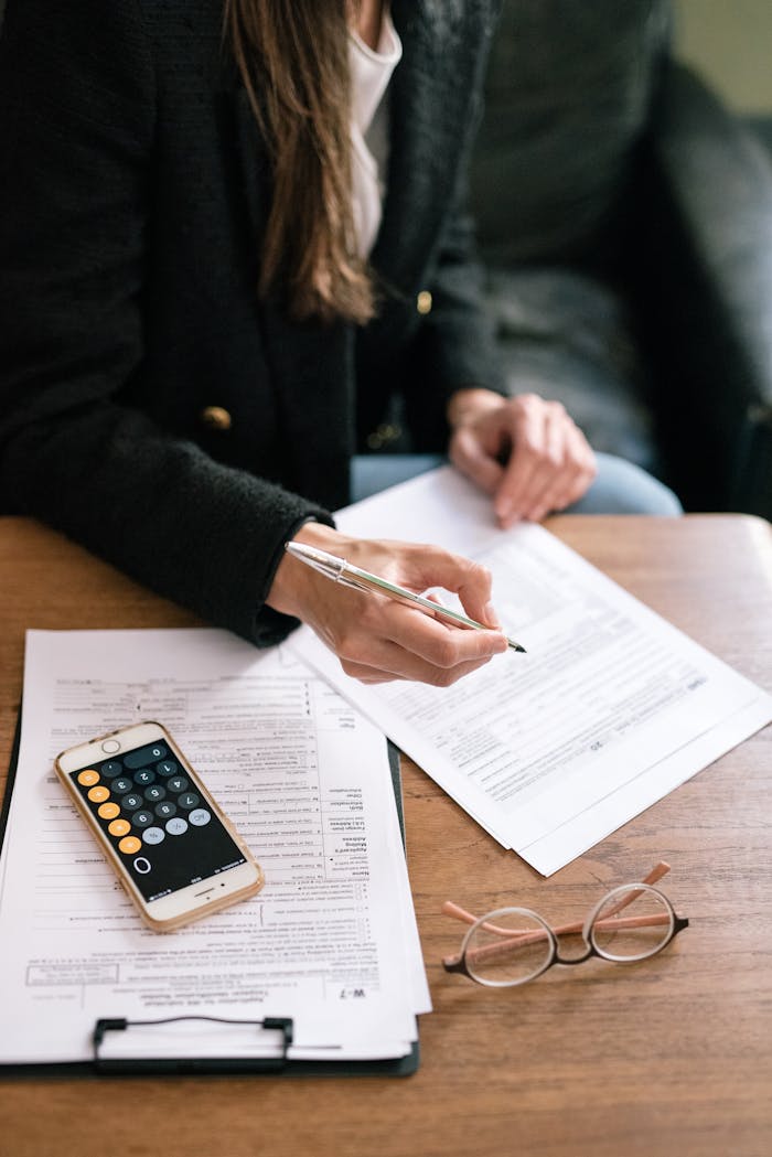 Crafting Captivating Headlines: Your awesome post title goes here A woman reviewing financial documents with a calculator and glasses on a table.